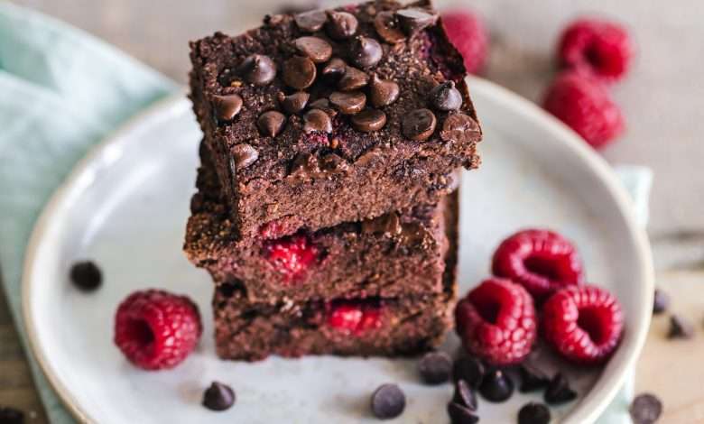 brownies top with chocolate chips with raspberry side inside a plate