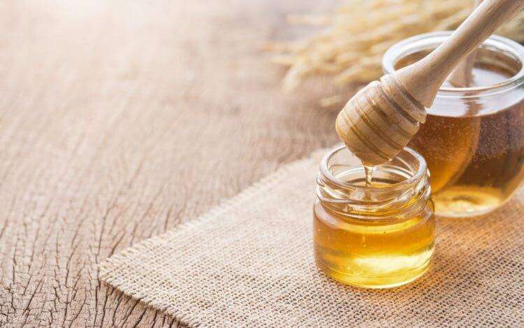 Honey dipping with a wooden honey dipper on a wooden table