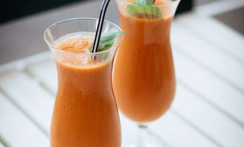 2 fruit juice in a glass with straw in the table